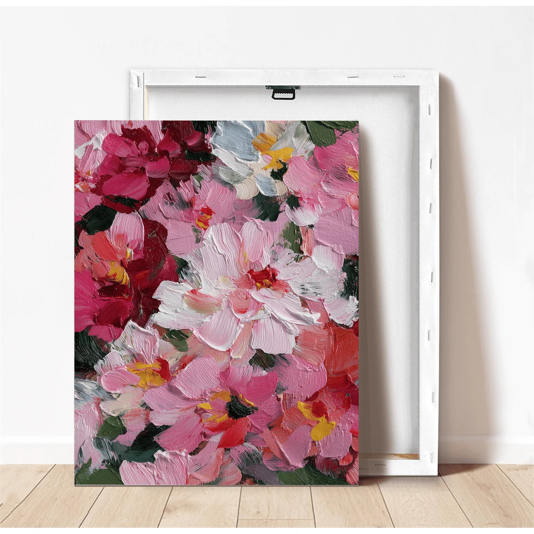 Framed pink and burgundy wildflower canvas wall art leaning against a cream wall