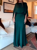 Deep green long gown shown from the front in a home interior
