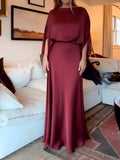 Front view of burgundy long gown showing glossy drape and flowing skirt indoors
