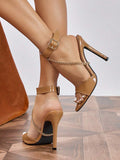 Tan patent peep-toe stiletto with ankle straps and gold chain accents