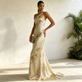 Three-quarter full-length view of champagne gown with gold botanical print, fitted silhouette and soft train against a light backdrop