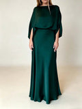Deep green glossy evening gown with boat neckline and flowing batwing sleeves, studio view