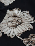 Close-up of black mesh fabric with champagne-silver 3D floral appliqué detail