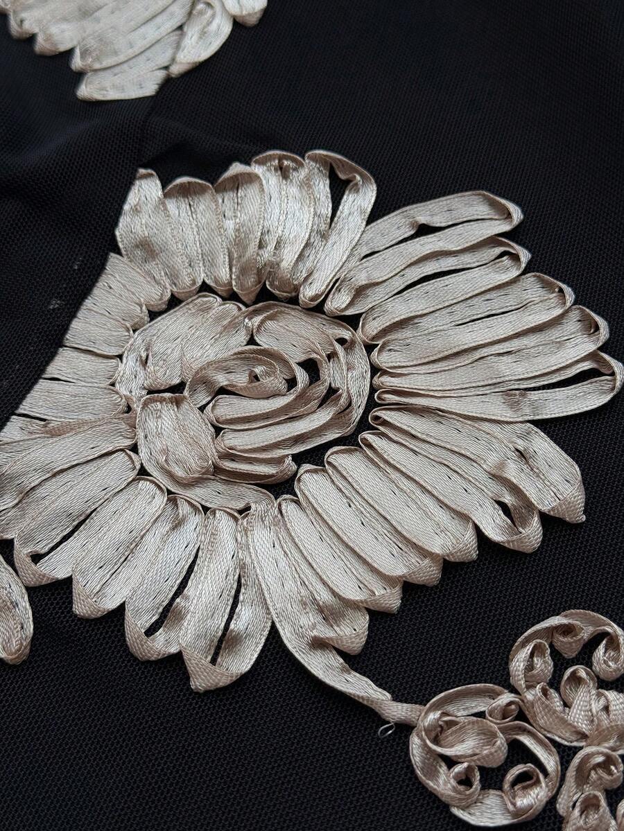 Close-up of black mesh fabric with champagne-silver 3D floral appliqué detail