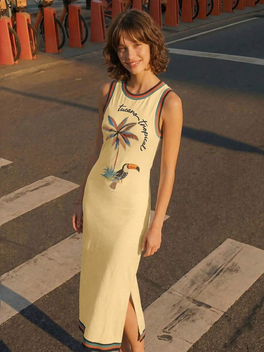 Elevated front view with side slit of butter yellow tropical toucan maxi dress by waterfront