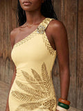 Close view of pale yellow one-shoulder neckline with floral brooch and botanical print