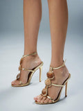 Front-side worn view of metallic gold scallop-shell T-strap square-toe stiletto sandals with ankle buckle for beach party styling