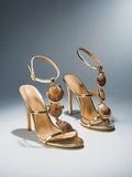 Front three-quarter pair view of metallic gold scallop-shell T-strap square-toe stiletto sandals with ankle buckle for beach party styling