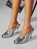 Silver worn close-up view of peep-toe stiletto mule sandals with a backless slip-on upper and slim high heel
