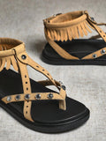 Close-up of beige fringe sandal straps with floral metal accents and toe-post detail