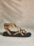 Side view of beige boho fringe ankle-strap sandal with black thick sole