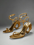 Pair of gold ankle strap sandals with circular sculptural heels in studio