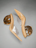 Top view of nude pointed mule heels with clear upper and gold wheel heel