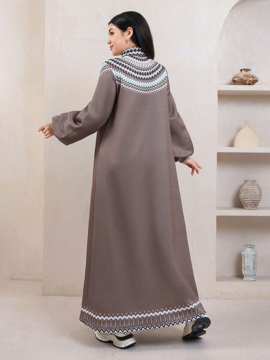 Front view of a model wearing a taupe ankle-length sweatshirt dress with geometric yoke, half zip and balloon sleeves