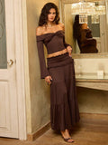 Indoor view of brown smocked-waist ruffle hem maxi skirt and off-shoulder knit top set