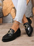 Side-top view of glossy black almond-toe loafers with thick soles and rhinestone buckles