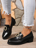 Front-side view of black rhinestone buckle block heel loafers worn on a wood floor