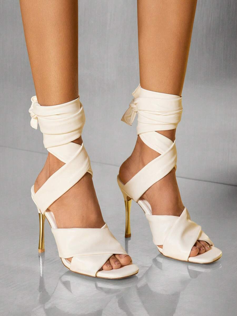 Close-up of white wraparound stiletto sandals with ankle ties