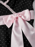 Close view of pink satin bow waist sash on black polka dot dress
