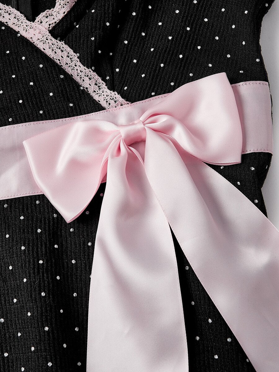 Close view of pink satin bow waist sash on black polka dot dress