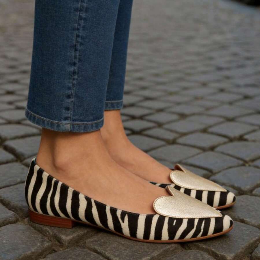Angled pair view of black-and-ivory zebra loafers with black heart appliques