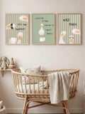 Set of three framed funny goose bathroom canvas prints above a wicker bassinet