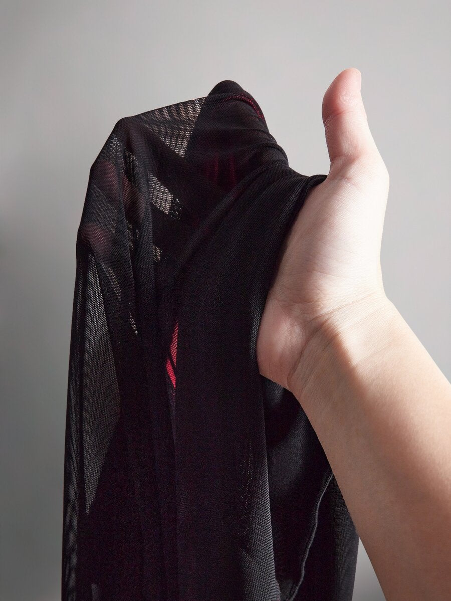 Close-up of sheer black mesh fabric from layered fairy hem of gothic mini dress