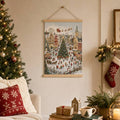 Hanging Christmas village canvas with wooden rails, decorated tree and snowy holiday market scene