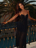 Front view of black spaghetti strap gathered bodice maxi dress on balcony