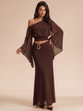 Brown asymmetrical two-piece outfit with smocked top, sheer sleeve, and flowing maxi skirt