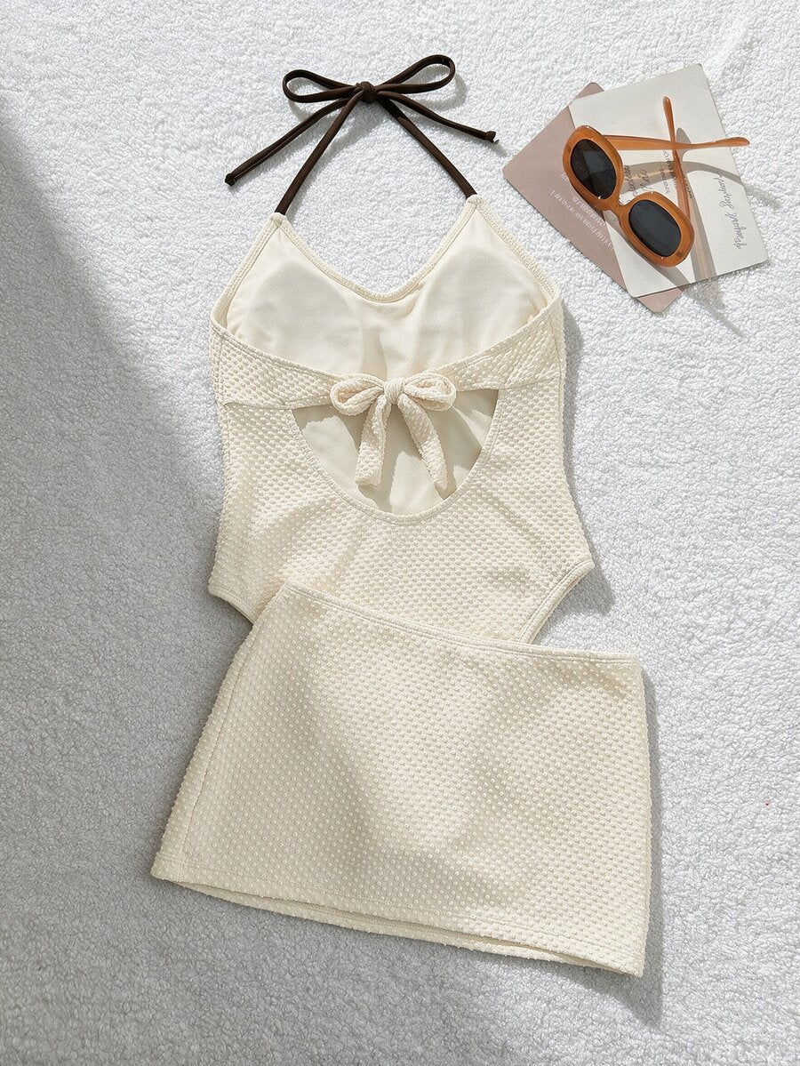 Back view of ivory halter one-piece swimsuit with open back bow and matching draped skirt