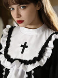 Close-up of white chest bib with black cross applique and black white gathered ruffle trim