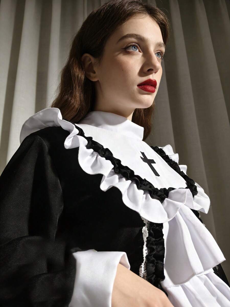Angled close-up of black sleeve and white ruffled chest bib with cross detail on cosplay dress