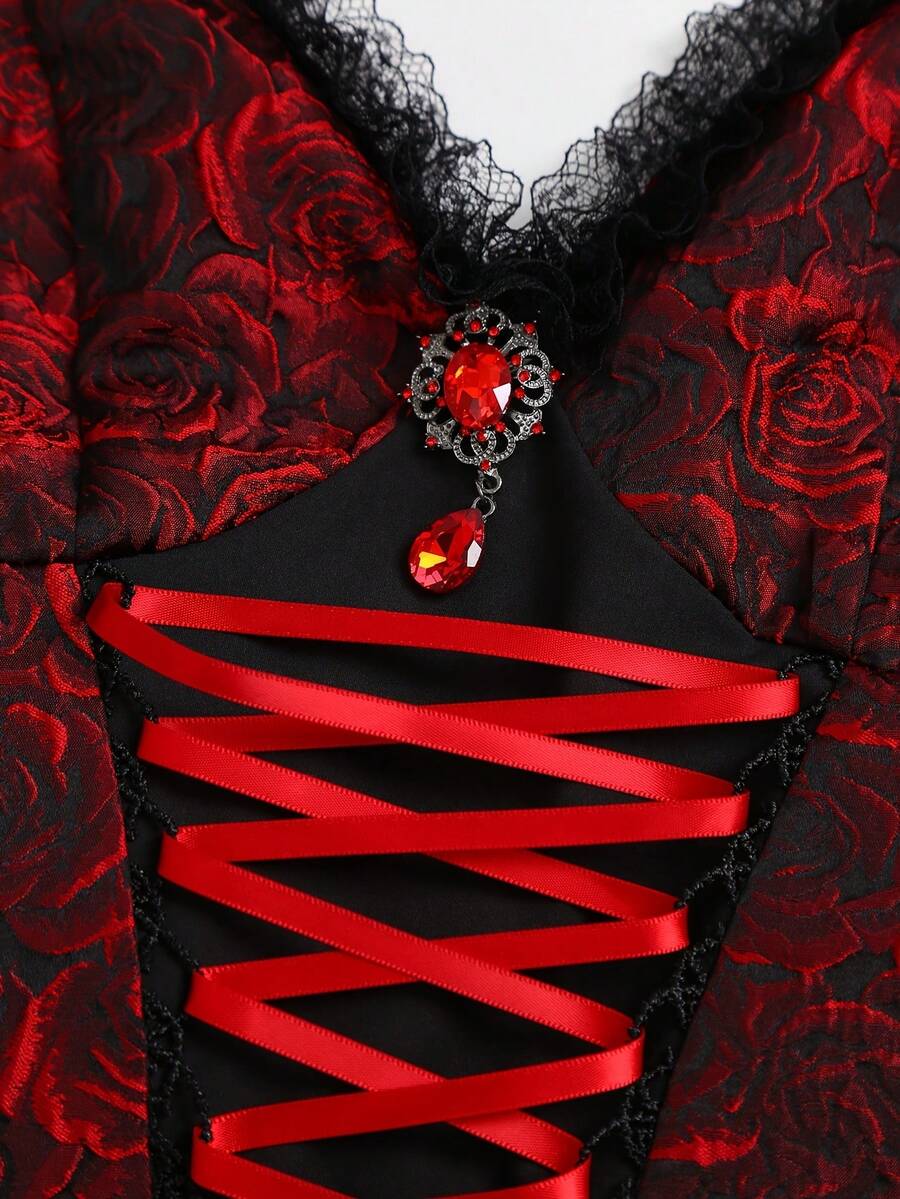 Close view of red gemstone pendant and red ribbon corset lacing on black mini dress