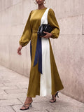 Outdoor full view of flowing olive and navy colorblock ankle-length dress