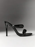 Side view of black patent open-toe mule with slim stiletto heel