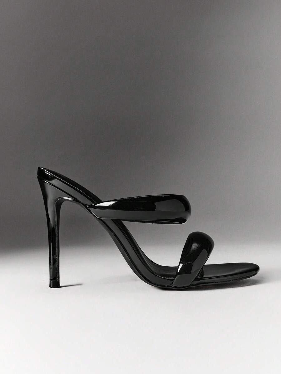 Side view of black patent open-toe mule with slim stiletto heel