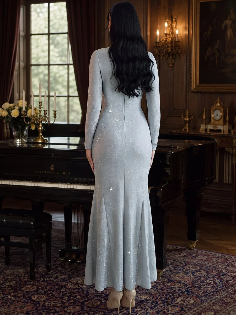 Full front view of a model in a sparkling silver-gray-blue long-sleeve mermaid evening gown with twisted waist in a piano room