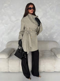 Full-length front outfit view of grey belted wrap coat styled with black trousers, gloves and handbag