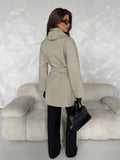 Rear three-quarter view of grey overcoat showing plain back panel, high wrap collar, waist belt and long sleeves