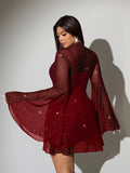 Rear view of red sparkling cover-up mini dress showing sheer sleeves and layered short hem