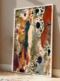 Angled view of a white-framed abstract canvas print leaning against a wall with rust, cream and dark teal shapes