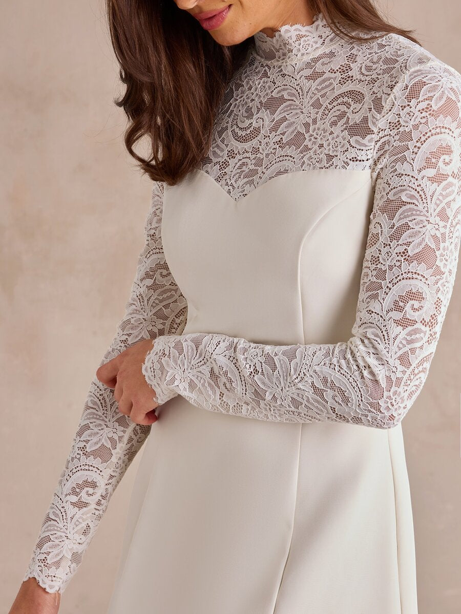 Close-up of floral lace stand collar, long sleeves, and curved ivory bodice seams