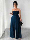 Model wearing navy jumpsuit, showing gathered strapless bodice and trousers