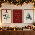 Three framed Christmas canvas prints with mistletoe, holiday quote and evergreen above a decorated mantel