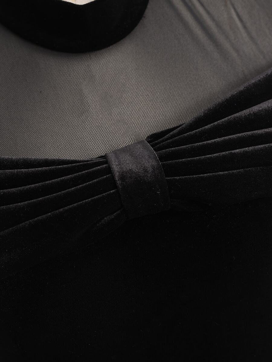Close-up of black dress showing sheer mesh and pleated velvet-look bow at neckline