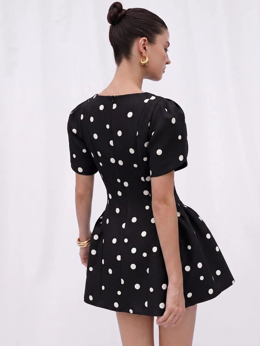 Back view of black and white polka dot dress with center zipper and puff sleeves