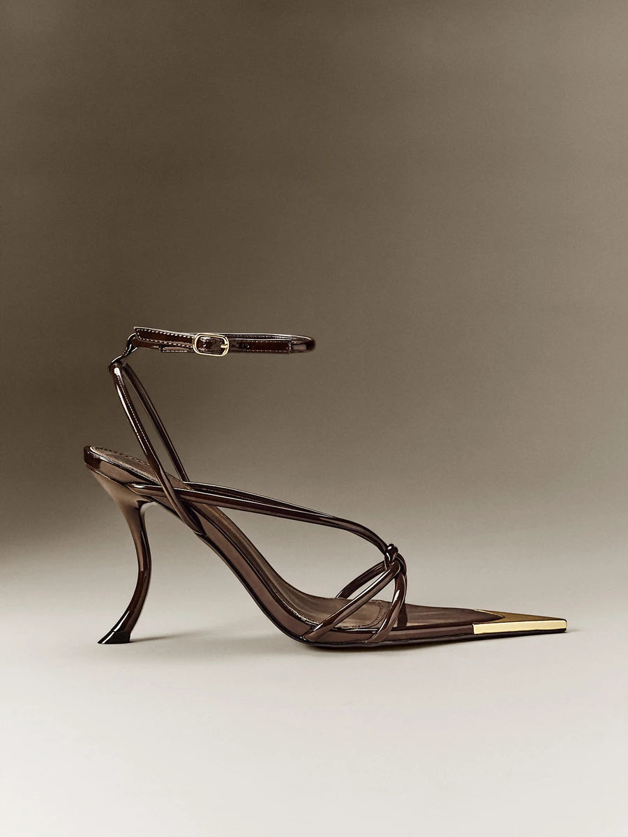 Side profile of chocolate-brown open-toe sandals showing curved stiletto heel and crossed straps