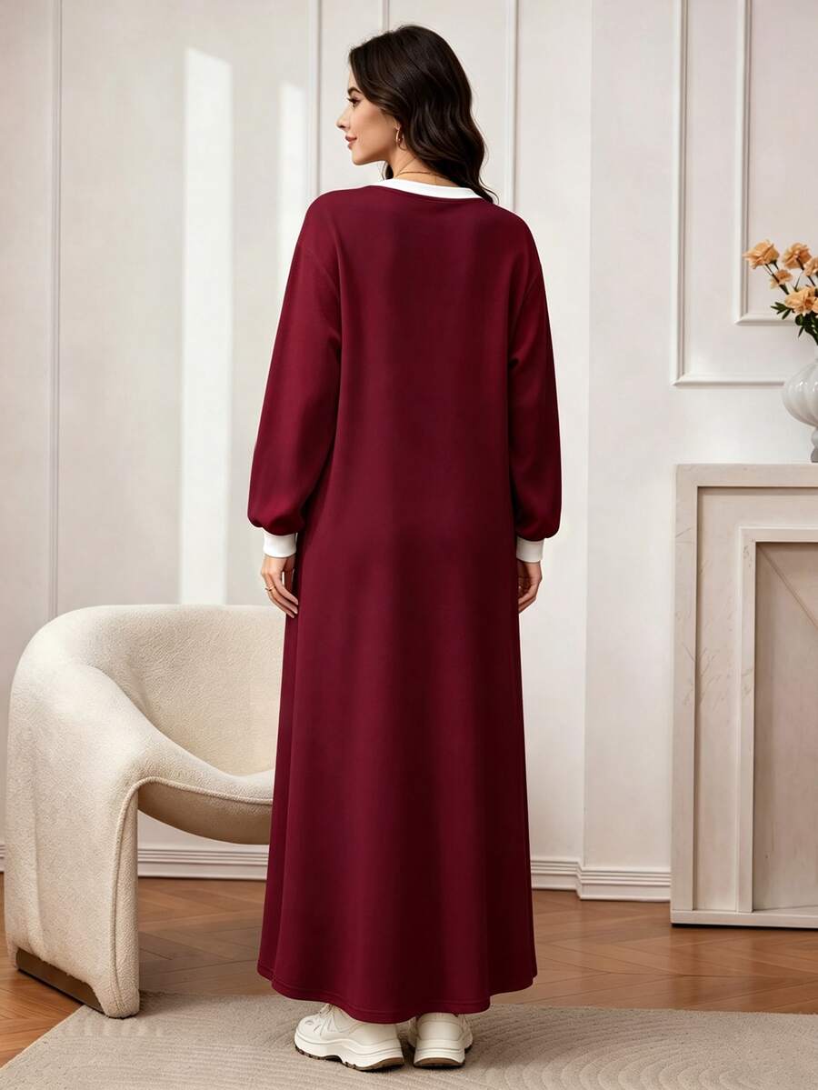 Front view of a model in a burgundy sweatshirt maxi dress with white crew neck, shoulder stripe and small chest embroidery