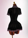 Back view of black fitted knit polo mini dress with geometric openwork pattern and pleated pink-striped hem
